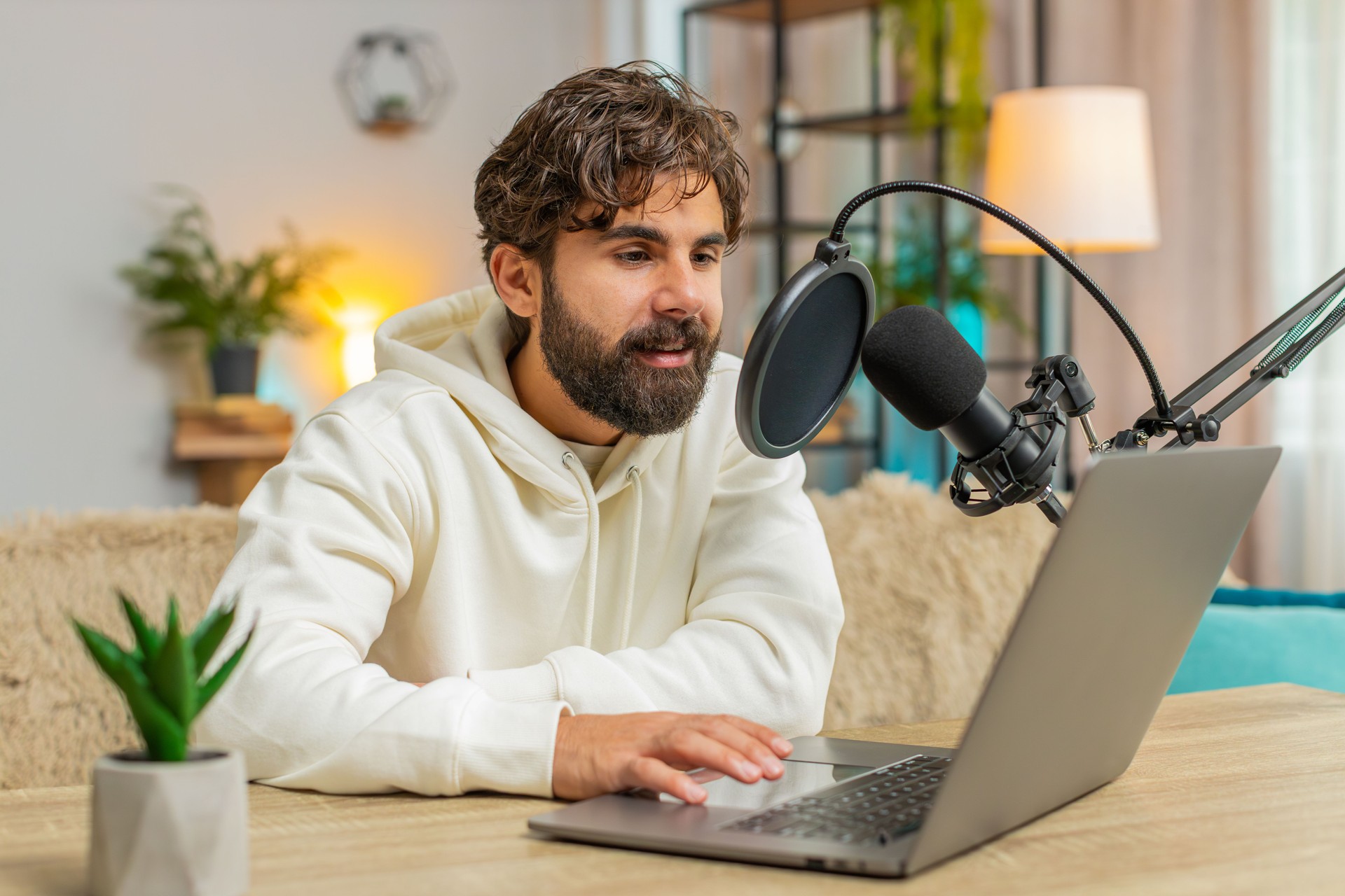 Happy blogger man recording podcast on sofa couch, giving workshop, webinar sitting on sofa at home