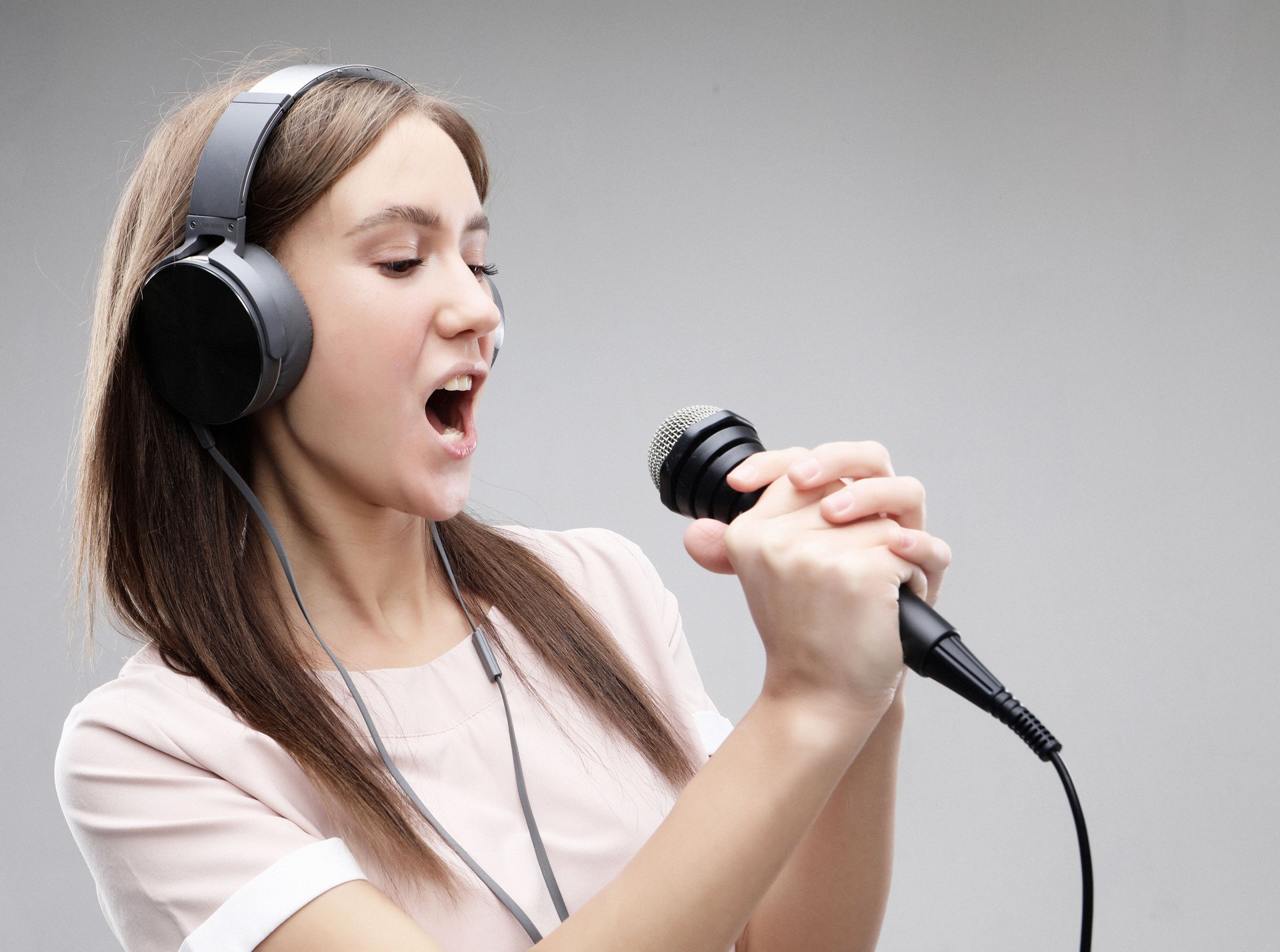 Ausdrucksstarkes Mädchen, das mit Mikrofon und Kopfhörern singt